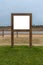 Wooden Advertising Frame By The River, in a Grass Field Under a Pale Sky