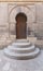 Wooden aged vaulted door, three steps and stone wall