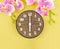 The Wooden alarm clock with pick color orchid on yellow background