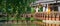 Wooden alcove near lake with ducks and trees. Garden house with reflection in water.