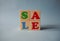 Wooden alphabet toy blocks with the text: sale. Isolated kids multi-colored ABC cubes on blue background