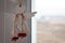 A wooden angel with a heart shaped hole hanging on a waxed cord on a window handle against a blurred background. Protective charm