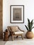 Wooden armchair near white stucco wall with three posters. Boho interior design with home decor