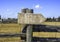 Wooden arrow sign board on rustic fence post in outdoor background, ready for text