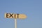 wooden arrow sign with the word exit. In the background the blue sky.