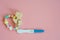 Wooden baby teether with beads and pregnancy test. Minimalistic flat lay with a wooden toys cat an isolated pink background. Toy f