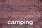 Wooden Background with Camping in White Letters