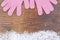 Wooden background with pink mittens winter snow on the border an