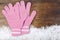 Wooden background with pink mittens winter snow on the border an