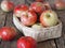 Wooden background with red early ripe apples in bulk and in a basket. Agricultural apple background