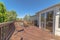 Wooden balcony with metal armchairs facing the sliding glass door of a home