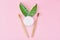 Wooden bamboo toothbrushes with baking soda powder in glass jar and green leaves on a pink background.  Teeth health and keep