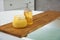 Wooden bath tray with sponge, soap bar and dispenser on tub