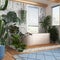 Wooden bathroom in white and blue tones with freestanding bathtub. Windows with venetian blinds. Biophilic concept, many