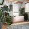 Wooden bathroom in white and gray tones with freestanding bathtub. Windows with venetian blinds. Biophilic concept, many