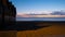 Wooden beach huts on beach at dusk, casting long shadows across the sand.