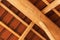 Wooden beams under a red brick roof during. Detail of wooden roof structure.