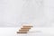 Wooden beige podium of square stands as ladder in elegant white interior with grey marble wall in sun light for cosmetics product