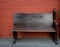 Wooden bench against red brick wall