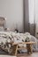 Wooden bench with books and flowers in the foot of the bed with grey bedding and cozy blanket