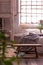 Wooden bench in front of bed in industrial bedroom interior. Real photo