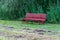 Wooden bench in the meadow. There are bushes behind the bench. Cut grass