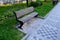 A wooden bench on the promenade in the park is sunk into the lawn in a paved niche. perennials bloom behind the bench and the lawn