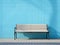 a wooden bench sitting against a blue wall