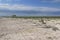 Wooden bench in the steppe. On the bench is a tourist backpack. Wooden gazebo. Blue sky, land covered with small shells, steppe