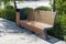 Wooden bench with wooden trash can in a park with green spaces on a summer day, nobody.