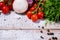 On a wooden bleached tabletop lies a set of vegetables for cooking