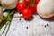 On a wooden bleached tabletop lies a set of vegetables for cooking