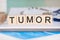 Wooden block form the word tumor with stethoscope on the doctor`s desktop. medical concept