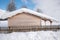 Wooden block house with snow covered roof and lattice fence