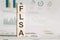 Wooden block with words FLSA - acronym FLSA - Fair Labor Standards Act