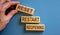 Wooden blocks form the words `reset, restart, reopening` on blue background. Male hand