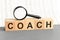 wooden blocks with the text coach, magnifying glass, concept