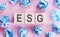 Wooden blocks with text ESG on pink background. ESG - short for environmental social governance