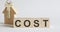 Wooden blocks with the word COST , house. The concept of the high cost of rent for an apartment or home