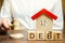 Wooden blocks with the word Debt and a miniature house with a judge`s hammer. Confiscation of property for failure to pay the deb