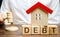 Wooden blocks with the word Debt and a miniature house with a judge`s hammer. Confiscation of property for failure to pay the deb