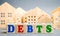 Wooden blocks with the word Debts and miniature houses. Debt concept for housing or mortgage. Real estate and credit, loan