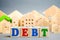 Wooden blocks with the word Debts and miniature houses. Debt concept for housing or mortgage. Real estate and credit, loan