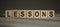 A wooden blocks with the word LESSONS written on it on a gray background