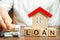 Wooden blocks with the word Loan, house and money in the hands of a businessman. The concept of buying an apartment or house in