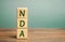 Wooden blocks with the word NDA - Non disclosure agreement. A legal contract entered into by two parties with limited access to