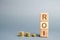 Wooden blocks with the word ROI and coins. High level of business profitability. Return on investment, invested capital, rate.