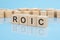 wooden blocks with the word ROIC, blue background