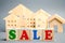 Wooden blocks with the word Sale and wooden miniature houses. The concept of the sell of real estate, apartments and residential