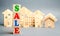 Wooden blocks with the word Sale and wooden miniature houses. The concept of the sell of real estate, apartments and residential